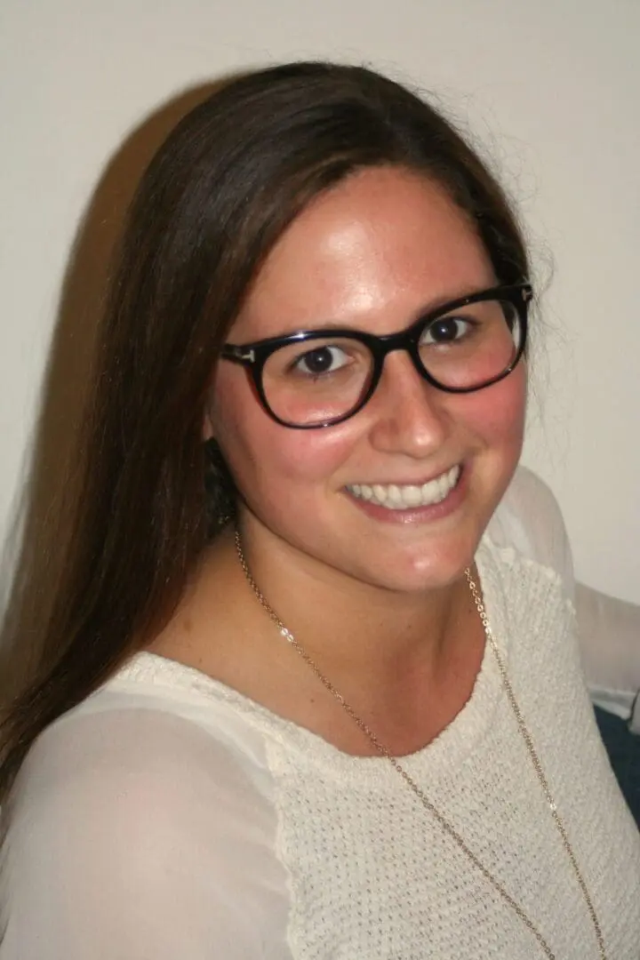 A woman with glasses smiling for the camera.