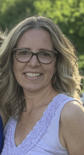 A woman with glasses smiling for the camera.