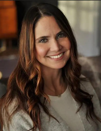 A woman with long brown hair smiles for the camera.