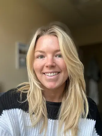 Smiling blonde woman in sweater.