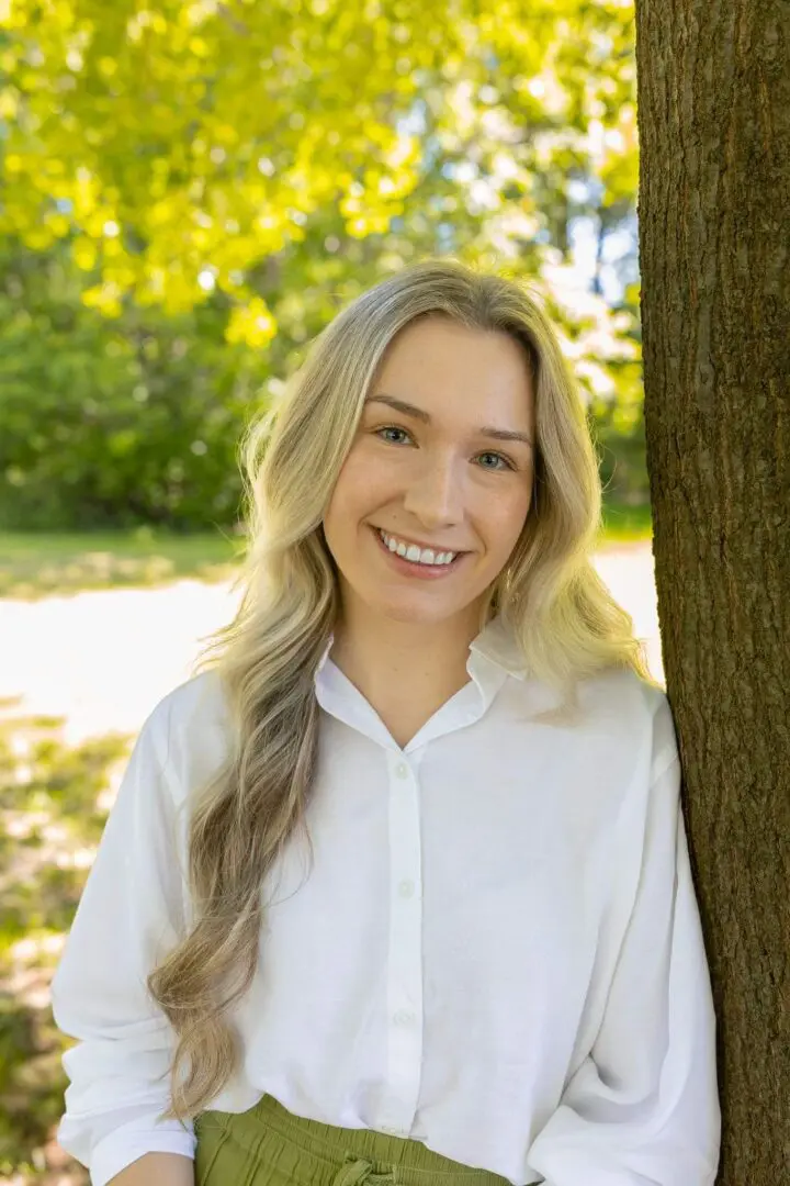 Smiling woman in white shirt, outdoors.