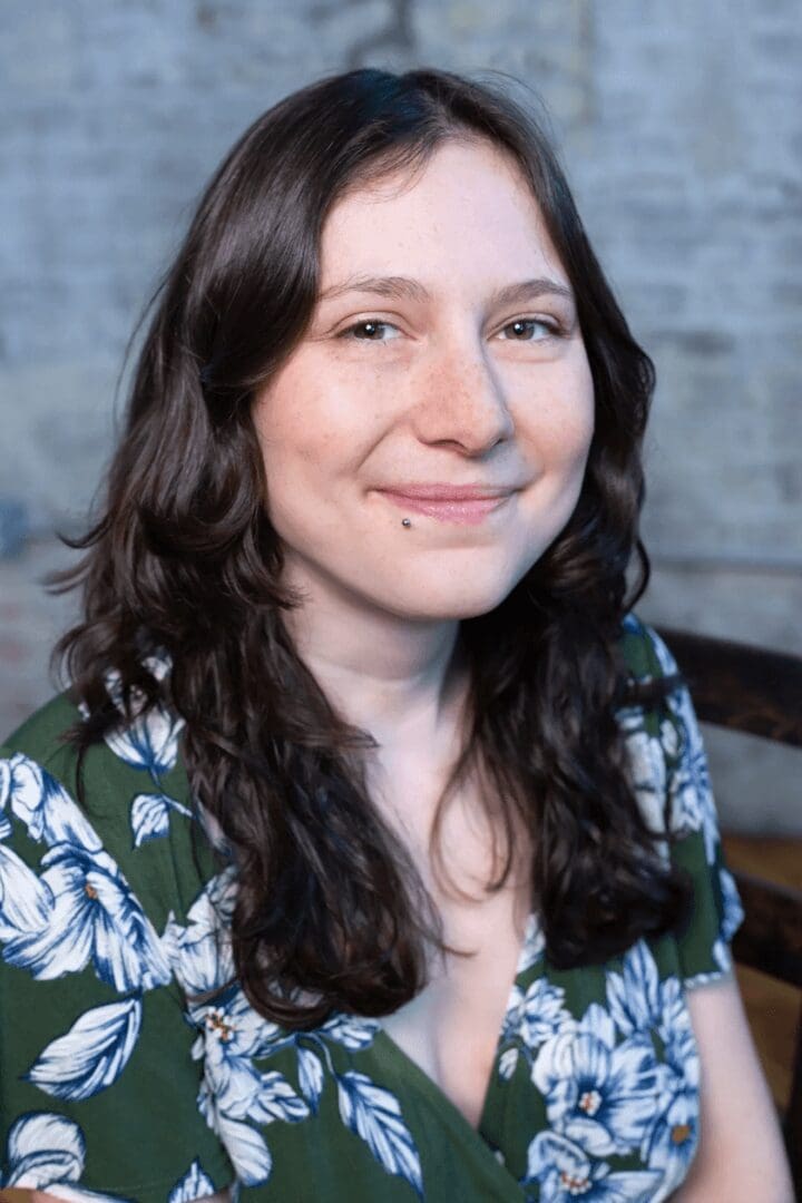 Smiling person with long hair and floral shirt.