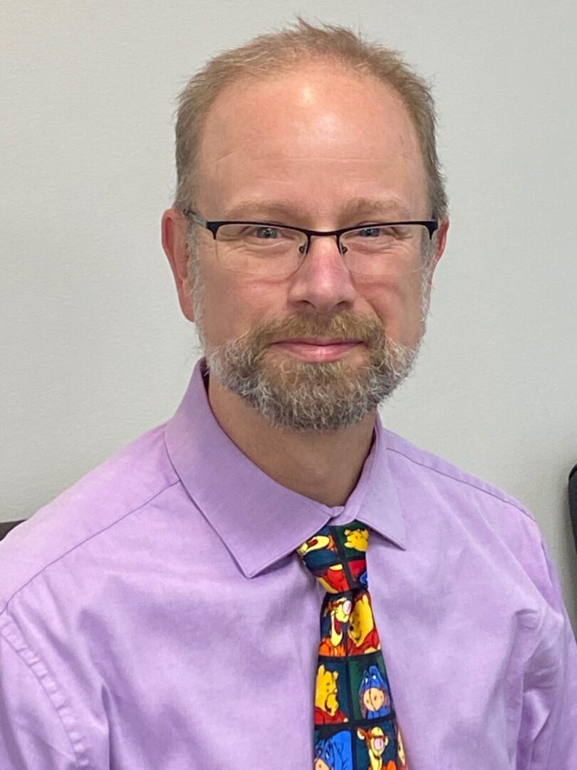Man wearing glasses and colorful cartoon tie.