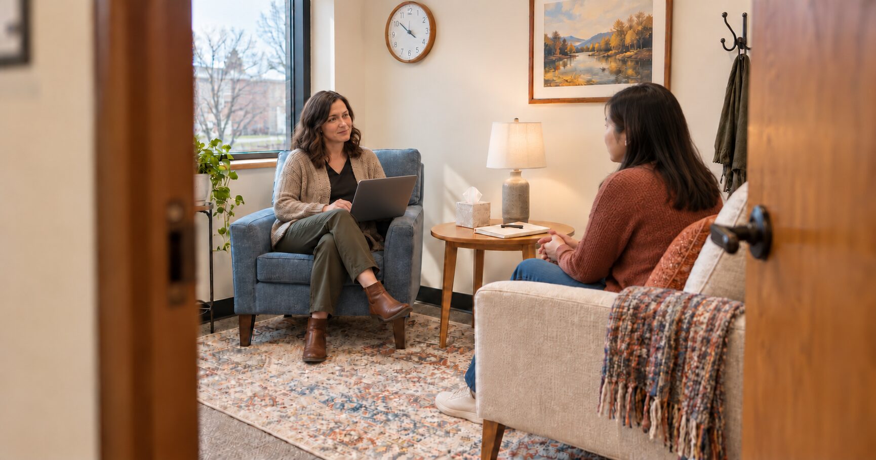 A therapist takes notes on a laptop during a first therapy appointment intake session