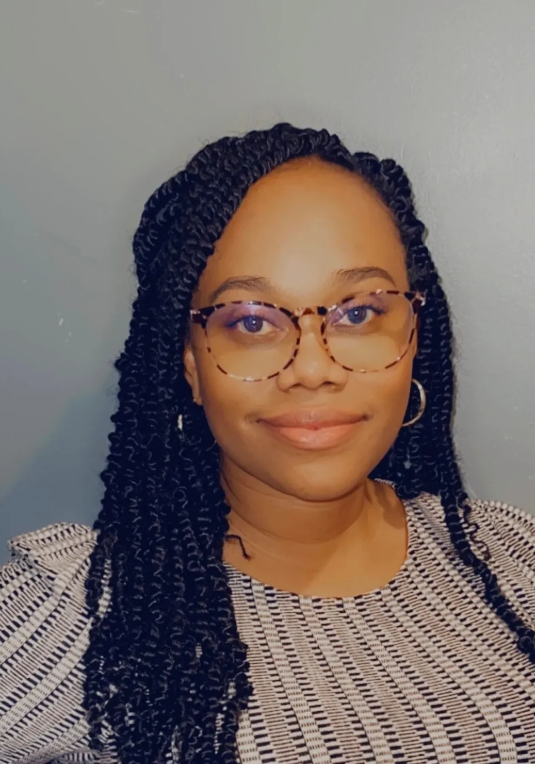 Person smiling with glasses and braided hair.