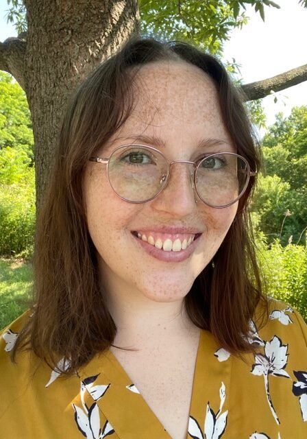 A woman with glasses smiling for the camera.