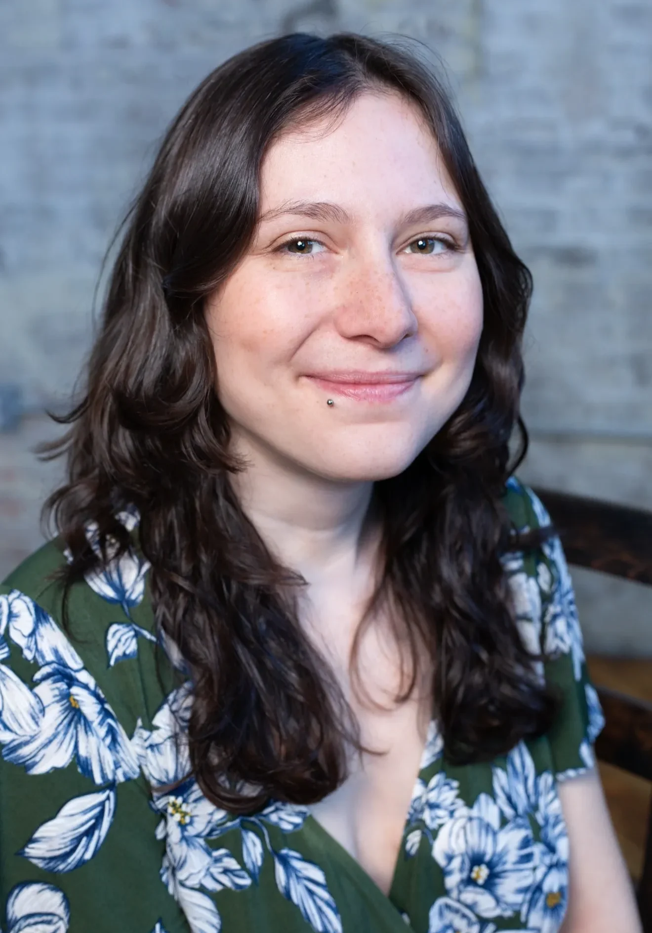 Woman smiling in floral-patterned dress.